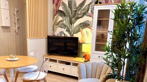 A modern living room with a sofa, a dining table, chairs, a TV, and a cabinet. - THE REMOISED ECRIN (Reims)