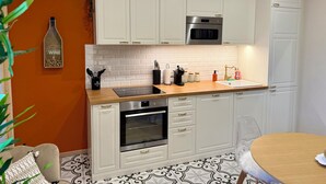 A modern kitchen with white cabinets, a stainless steel oven, and a wooden countertop. - THE REMOISED ECRIN (Reims)