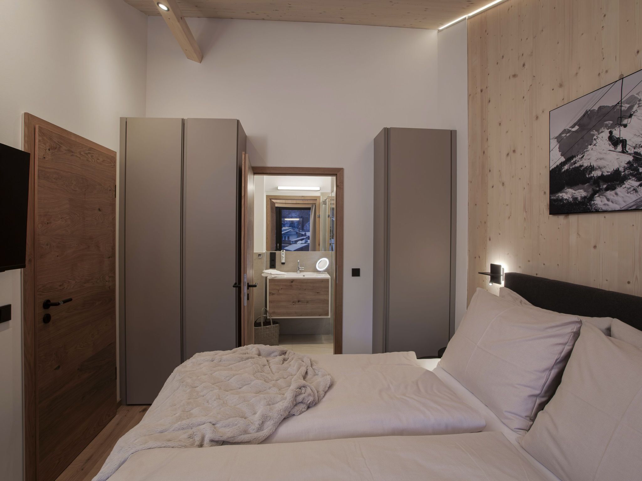 A bedroom with a bed, a mirror, a wardrobe, and a painting on the wall.