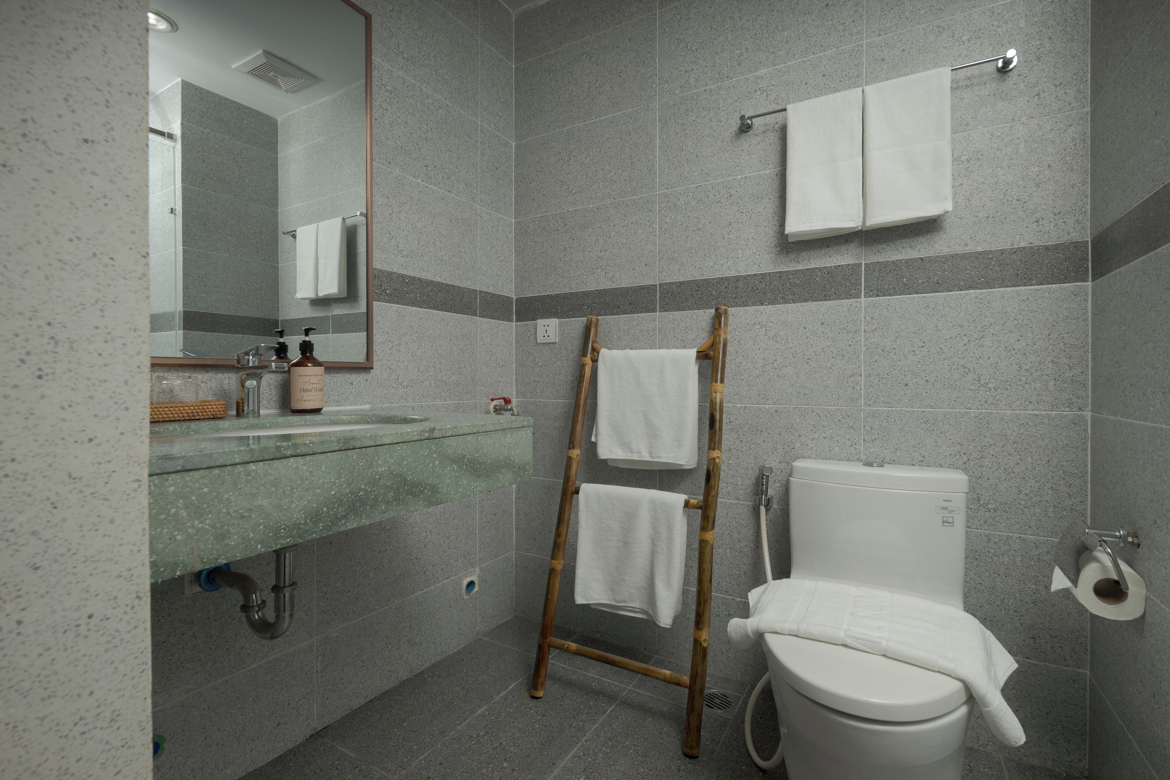 A bathroom with a toilet, a sink, a mirror, and a towel rack.