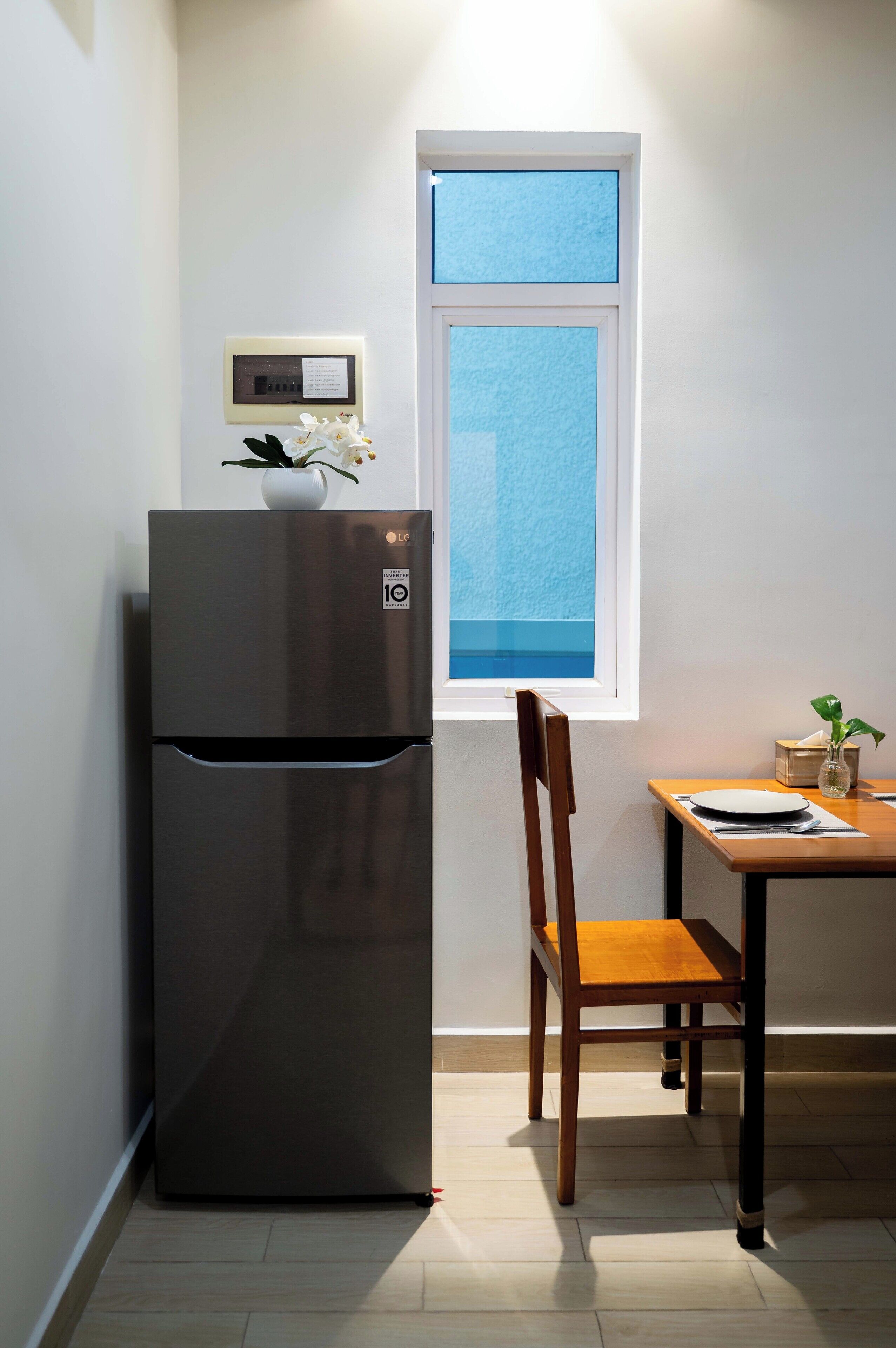 Una cocina compacta con refrigerador incorporado, ventana con vistas, mesa de comedor de madera y una silla.