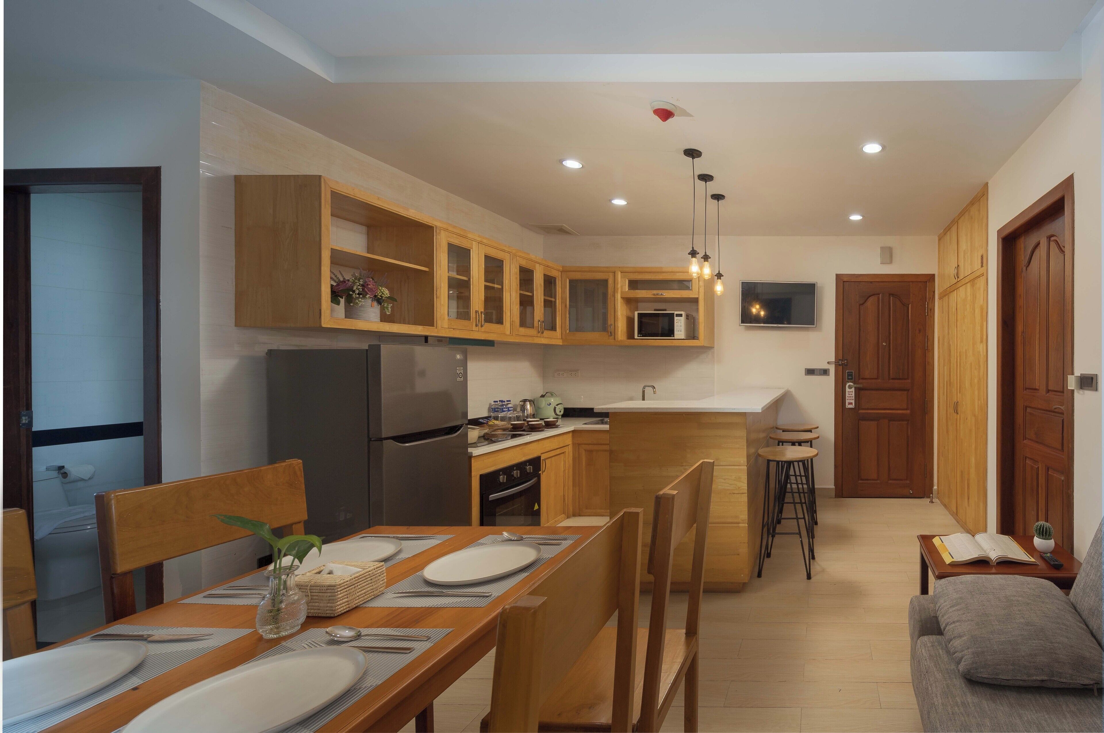 Une cuisine moderne avec des meubles en bois, un four à micro-ondes encastré et un réfrigérateur.