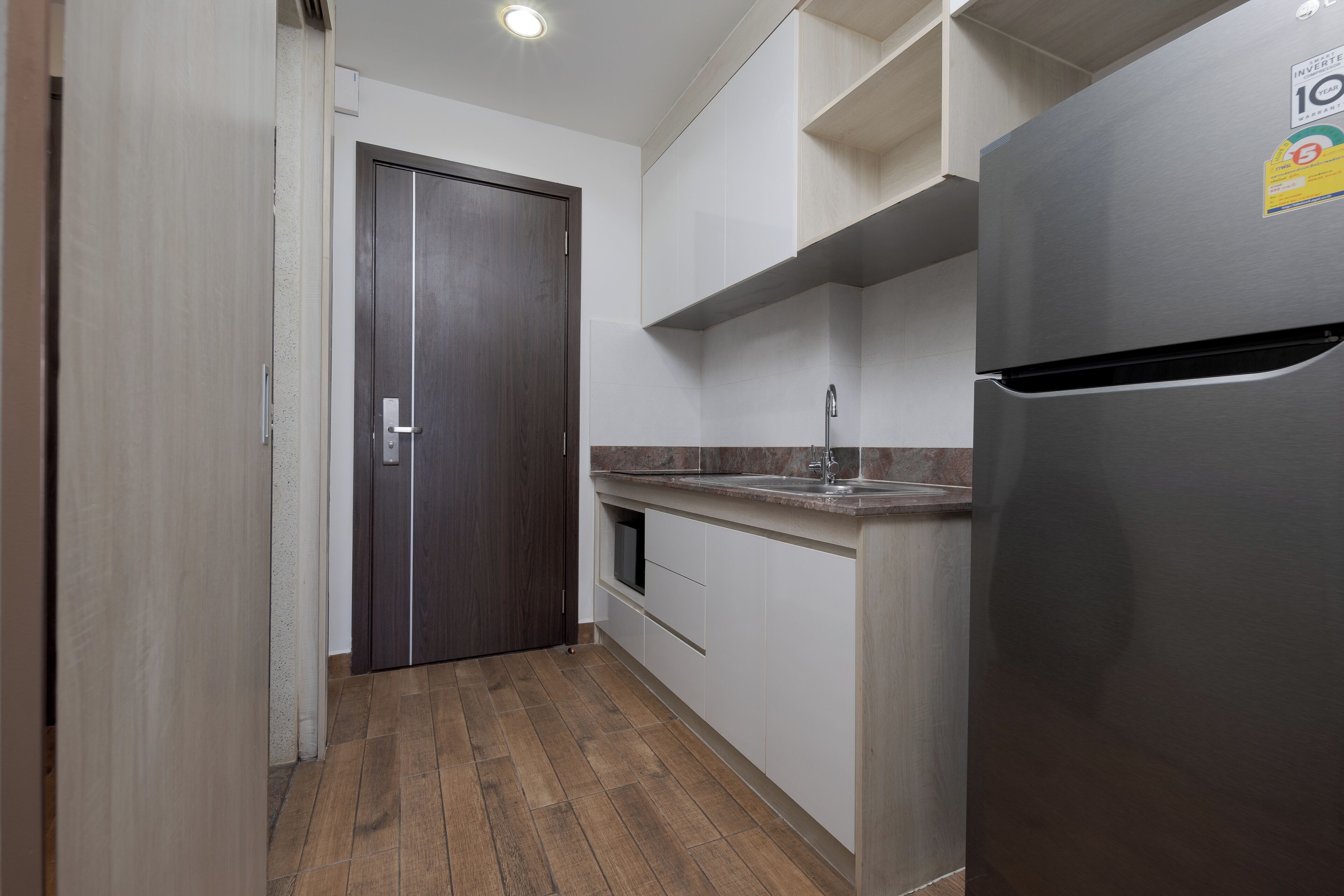 Una cocina con refrigerador de acero inoxidable, puerta de madera y encimera con lavamanos.