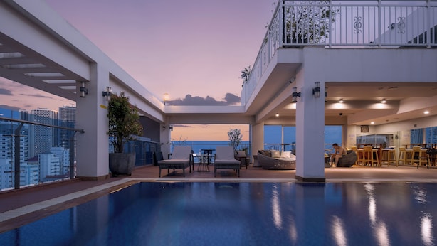 A rooftop pool area with a city view, seating, and a bar/lounge area.