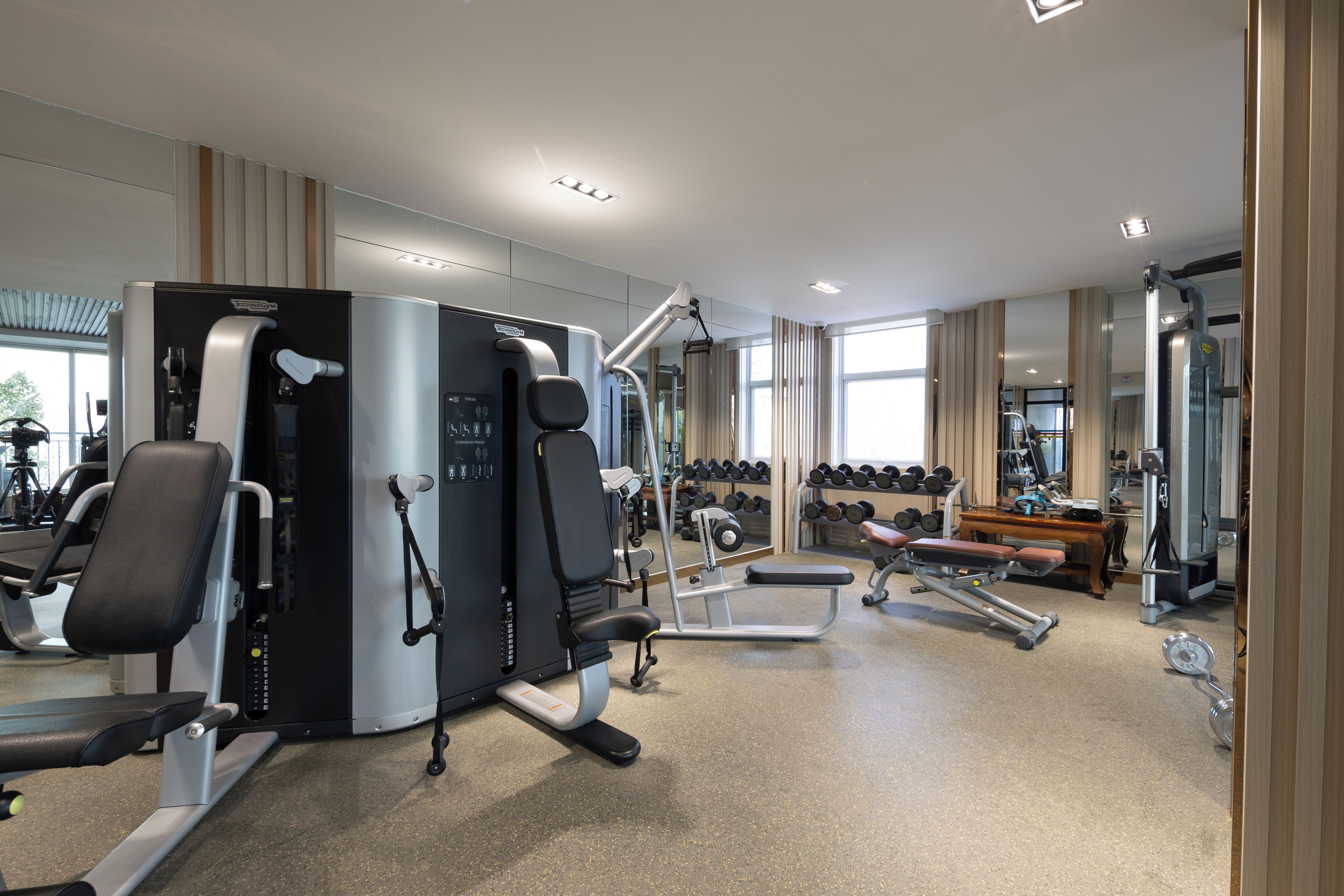 Ein modernes Fitnessstudio mit verschiedenen Trainingsgeräten, darunter Kraftgeräte und Kurzhanteln.