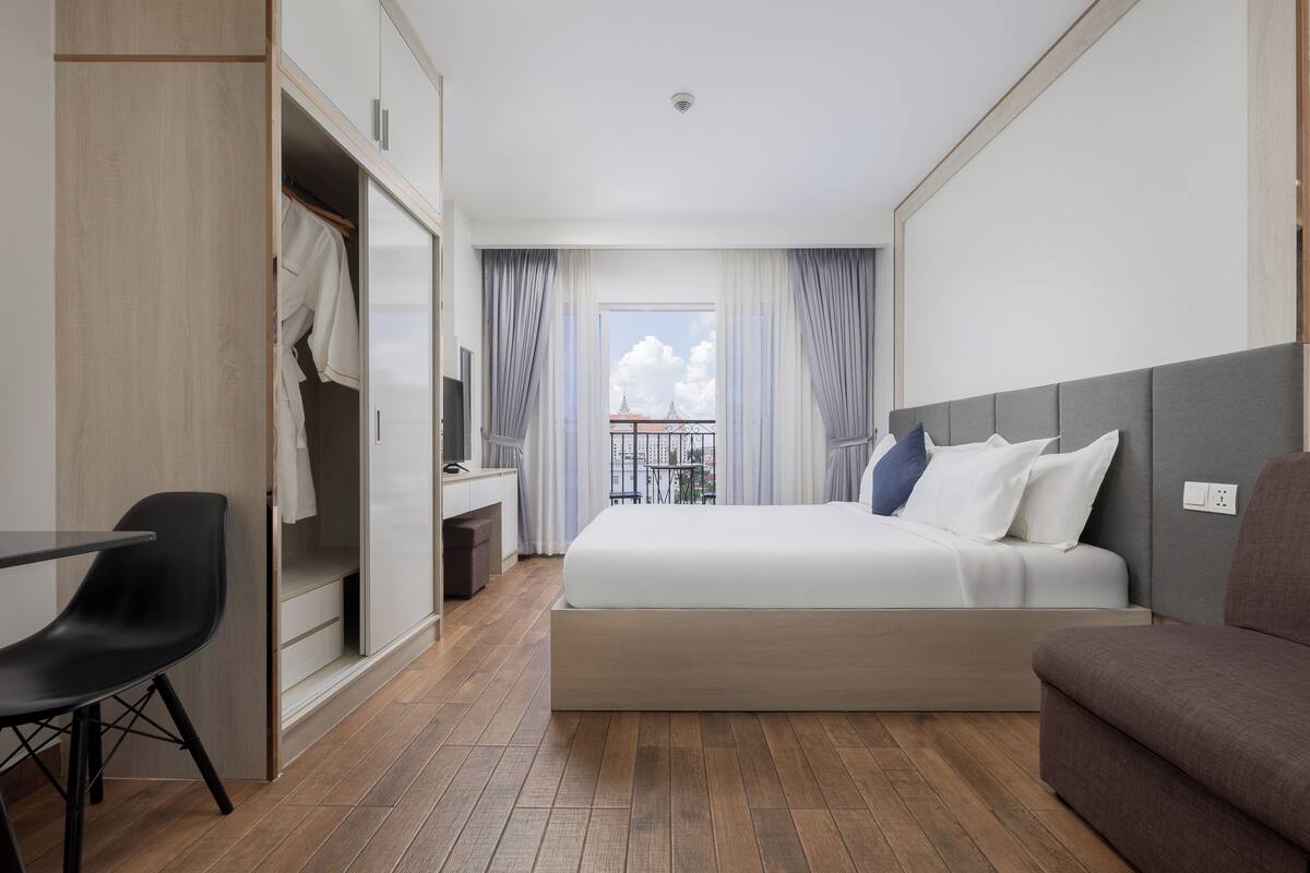 A hotel room with a bed, a desk, a chair, and a wardrobe.