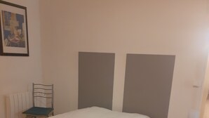 A bedroom with a large bed, a chair, a small table, and a radiator.