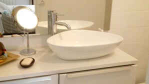 A bathroom with a white sink, a round mirror, and a toilet.