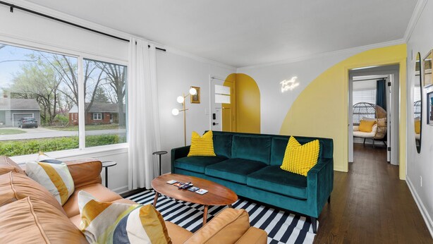 En moderne stue med en turkis sofa, stribet måtte og udsigt ud.