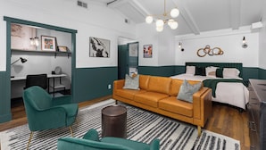Et moderne værelse med grønne og hvide farver, med en sofa, et skrivebord og en seng.