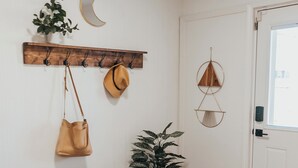 En gang med et træklædestativ, en bænk, en potteplante og vægdekorationer, heraf en halvmåne og geometriske former.