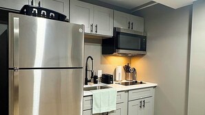 A modern kitchen with stainless steel appliances, grey cabinets, and a wooden floor. - 1BR Oasis Escape in SE Atlanta (Atlanta)