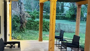 An outdoor covered patio area with concrete flooring, wooden pillars, and black wicker furniture. - 1BR Oasis Escape in SE Atlanta (Atlanta)