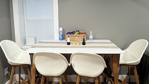 A dining area with a table and four chairs, a window with blinds, and a basket of snacks on the table. - 1BR Oasis Escape in SE Atlanta (Atlanta)