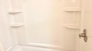 A white bathtub with a showerhead and a door handle. - Big Red motel (Laurel)