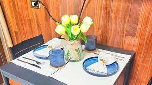 Una mesa de comedor dispuesta con platos azules, un jarrón de tulipanes amarillos y candelabros azules.