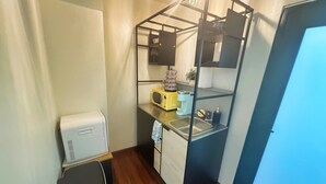 Una cocina compacta con microondas integrado, cafetera y lavamanos.
