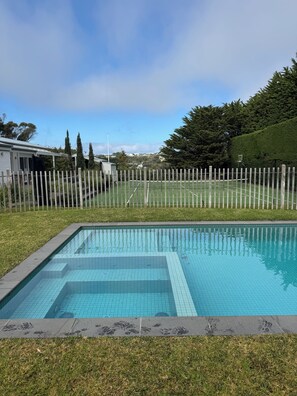A swimming pool with a wooden fence, surrounded by grass and trees. - Resort-style 4-bedroom, tennis court, pool, spa, gardens, alfresco in Portsea (Portsea)