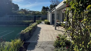 Un espace extérieur aménagé avec une piscine, une terrasse en bois et un jardin agrémenté de plantes à fleurs.