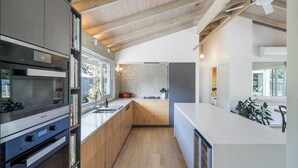 Une cuisine moderne avec des meubles en bois, un four encastré et un grand îlot central doté d’un évier.