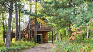 A cabin surrounded by trees with a gravel path leading to the entrance. - Fish, Hike & More: Cozy Brainerd Cabin (Brainerd)