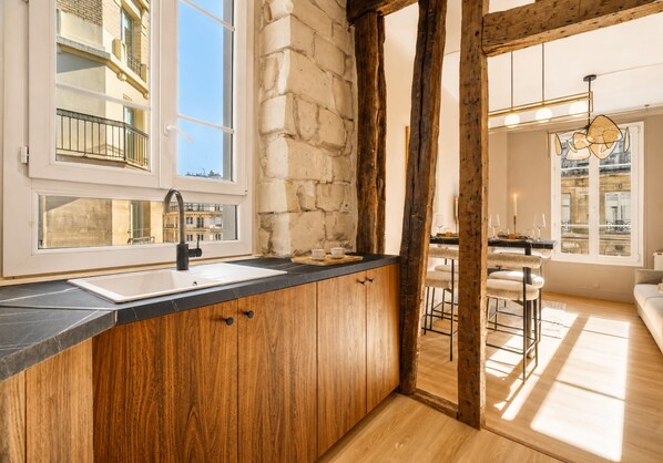 Une cuisine moderne avec un mur en pierre, des armoires en bois et une grande fenêtre.