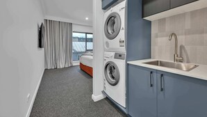 Une chambre d’hôtel moderne équipée d’une machine à laver, d’un lavabo et d’un lit.