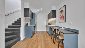 Une cuisine moderne dotée d’un îlot central intégré, d’un coin repas avec des chaises et d’un escalier menant à un autre niveau.