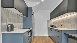 Une cuisine moderne avec des meubles gris, un plan de travail blanc et un plancher en bois.