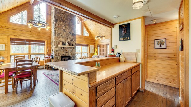 Une cuisine spacieuse avec des meubles en bois, un grand îlot central et une cheminée en pierre.