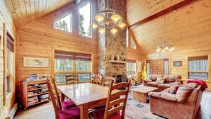 L’intérieur d’un chalet en bois comprend un coin repas, un canapé et une cheminée en pierre.