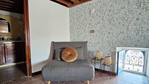 A room with a grey sofa, a wooden ceiling, a patterned wall, and a tiled floor. - Beit El Ezz Kerkennah  (Kerkennah Islands)