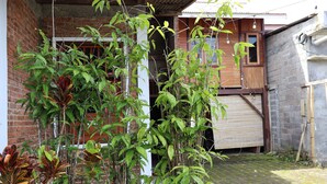 A brick building with a garage door, surrounded by greenery and a paved area. - Chrisma Bed and Breakfast (Tomohon)