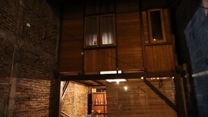 A wooden interior with exposed brick walls and a staircase leading to a second floor. - Chrisma Bed and Breakfast (Tomohon)