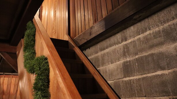 A wooden staircase with a brick wall adjacent to it. - Chrisma Bed and Breakfast (Tomohon)