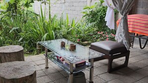A glass-top table with books and a vase, a brown stool, and a striped tablecloth. - Chrisma Bed and Breakfast (Tomohon)