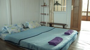 A bedroom with a bed, pillows, a nightstand, a shelf, and a door. - Chrisma Bed and Breakfast (Tomohon)