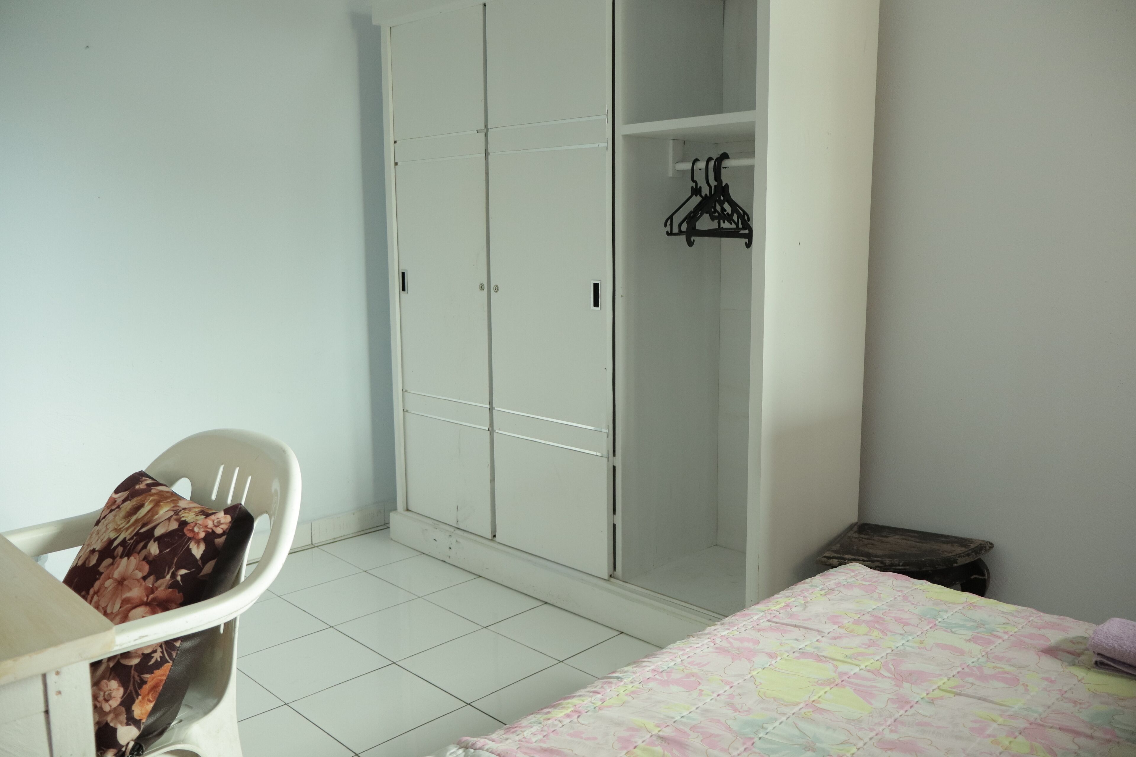 Une chambre à coucher avec un lit, une chaise, une armoire et un petit tabouret.