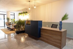 A modern reception area with a wooden reception desk, a blue accent wall, and hanging plants.