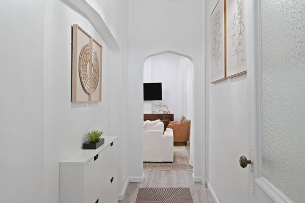 A hallway with a white dresser, a plant, and framed artwork on the wall.
