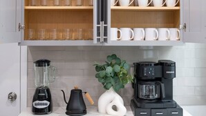 Une cuisine équipée d’une machine à café, d’un mixeur et d’une bouilloire, le tout posé sur le plan de travail.