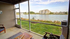 A room with a large window overlooking a lake and a building across the water. There is a wooden bench and a chair inside the room. - Pet Friendly, Includes Pool, Kids' Pool, & Free* Golf & Activities, 10 Mins to Beach, 1st Fl. (Ocean View)