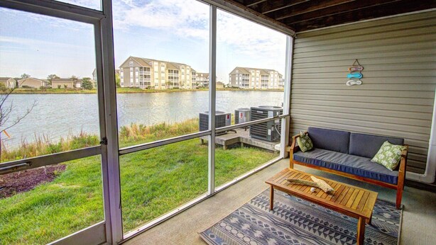 A balcony with a view of a lake, a sofa, and a table. - Pet Friendly, Includes Pool, Kids' Pool, & Free* Golf & Activities, 10 Mins to Beach, 1st Fl. (Ocean View)