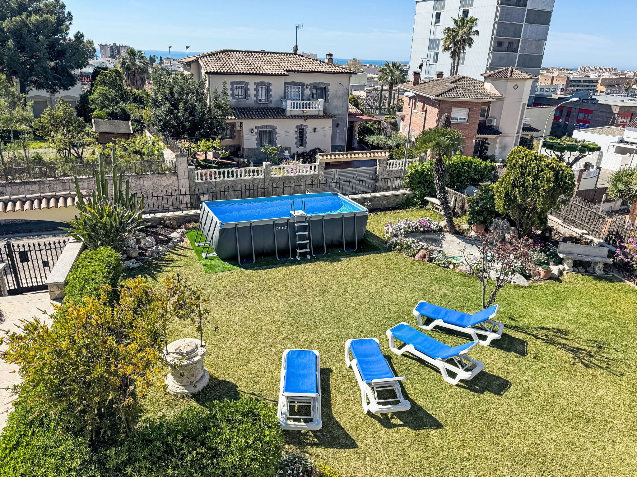 Un quartier résidentiel doté d’une piscine, de chaises longues et d’une fontaine en pierre.