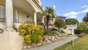 A classical building with a stone wall, columns, and a covered porch.