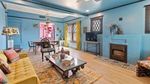 A living room with a blue wall, a yellow sofa, a coffee table, and a fireplace. - Stylish "NEW" Home- Hot Tub - Near Downtown, PHX Airport, and ASU (Phoenix)