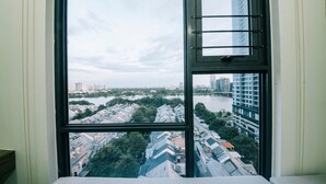 A room with a large window offering a view of a river and surrounding buildings. - Sunwah Pearl Suites  (Ho Chi Minh City)
