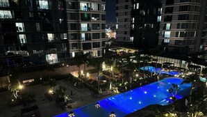 A nighttime view of a swimming pool with blue lighting, surrounded by palm trees and buildings. - Sunwah Pearl Suites  (Ho Chi Minh City)