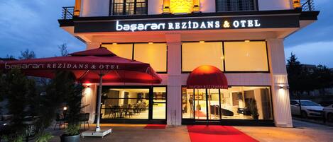 A hotel with a red carpet entrance, outdoor seating, and a large awning.