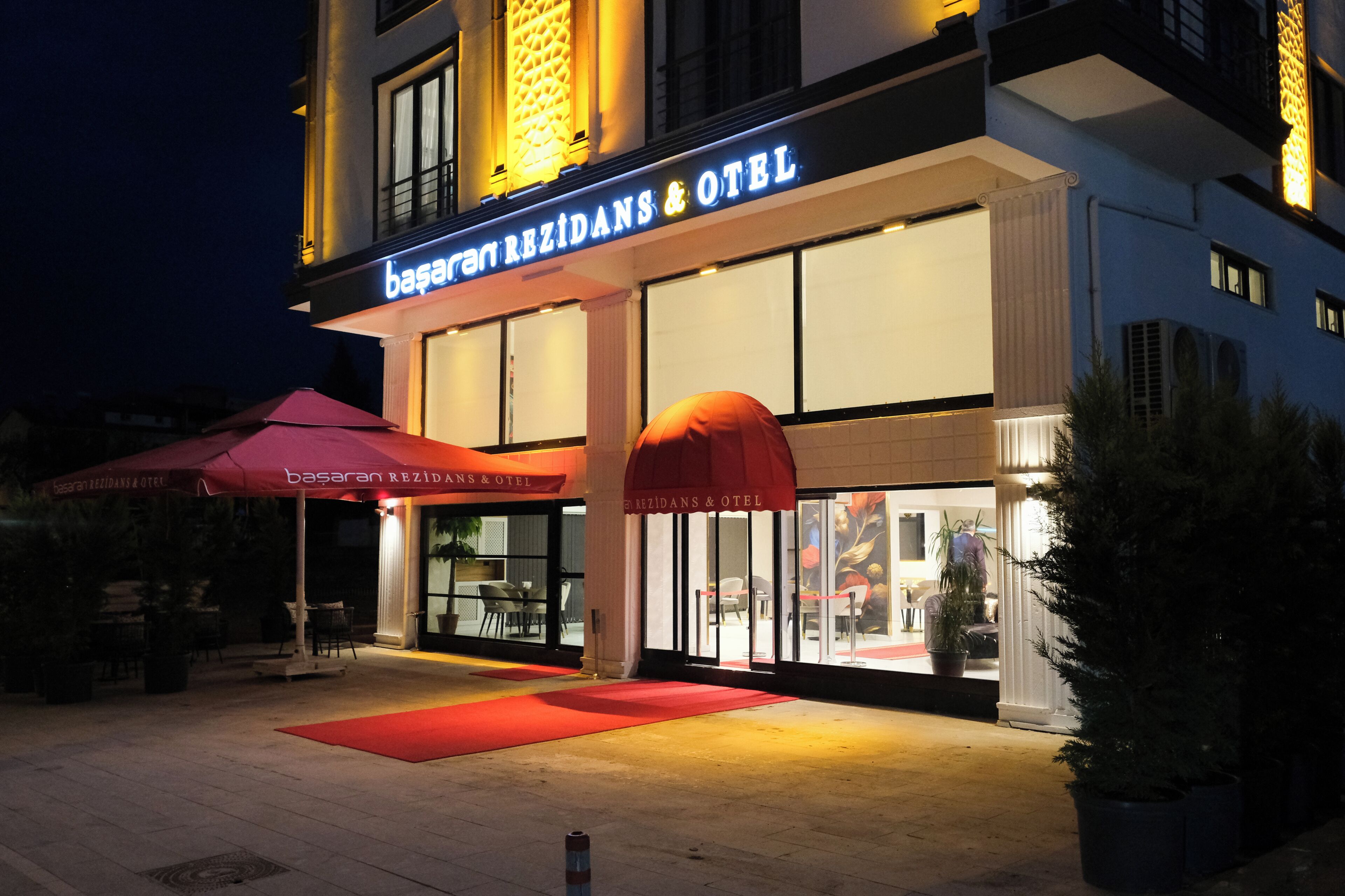 Entrada de hotel con un toldo rojo y una alfombra roja que conduce a las puertas.